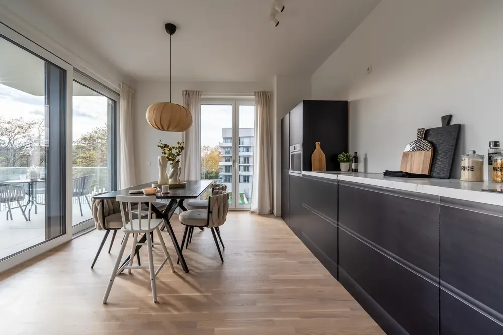 Moderne Küche mit Essbereich in einer Wohnung am Albertussee in Düsseldorf, ausgestattet mit einem eleganten Tisch, bequemen Stühlen und großen Fenstern, die viel natürliches Licht bieten.