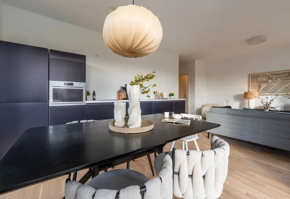 Moderne Küche mit einem schwarzen Esstisch, eleganten Stühlen und einer auffälligen Lampe in einer Wohnung am Albertussee, Düsseldorf.