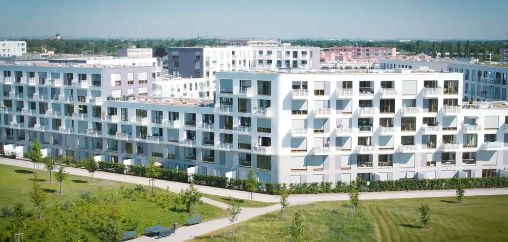 Moderne Wohnanlage mit mehreren Gebäuden, umgeben von Grünflächen und Gehwegen.
