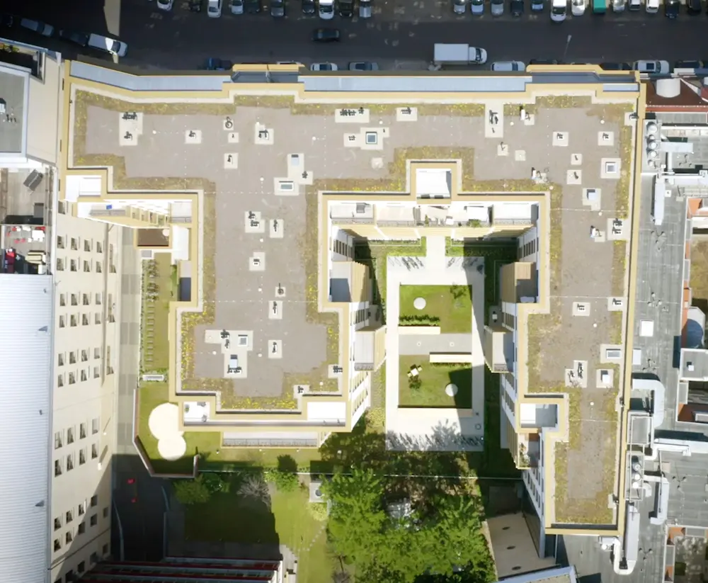 Luftaufnahme eines modernen Gebäudekomplexes mit begrünten Innenhöfen und Terrassen.